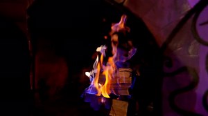 Blue and orange flame in modern fireplace. Wooden logs burning in brick fireplace.