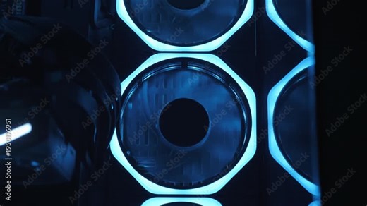 Gaming PC glowing in the dark - the system unit of a modern gaming computer. The working of the computer cooling fan can be seen through the blue lights. Fans are spinning inside the computer.
