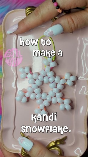 Pastel (kei), Roach, Honey on Instagram: "How to make a kandi snowflake!! You will need white pony beads, elastic string, scissors and a plastic needle is optional but very helpful. First cut your elastic string and string 12 pony beads. Tie your string tight and cut off the shorter string end. Add three white beads to your string and skip the bead next to your string and go through the next bead. Pull tight and repeat this process all the way through. Then it should look like this. Take your st