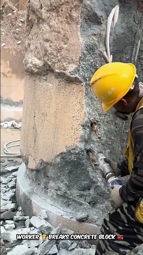 Worker Using Hammer Drill to Break Concrete Block on Construction Site