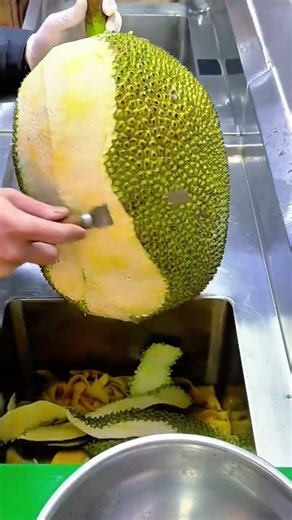 Peeling Thick Green Skin of a Large Jackfruit with a Sharp Knife for Fresh Fruit Prep