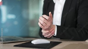 Close up. Office worker holding wrist in pain while using computer mouse. Concept of ergonomic challenges or repetitive strain injury in a professional work environment. Health of office professionals