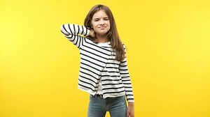 Funny child girl against an orange background suffering neck pain due to excessive computer use
