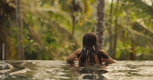 Couple Relaxing in Tropical Infinity Pool with Lush Jungle View