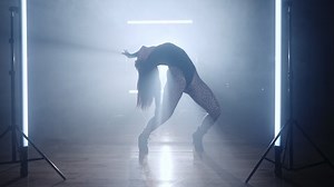 Mujer hermosa bailando sexy sola en estudio con humo y luces brillantes, lámparas. Dama moviendo activamente su cuerpo y su pelo al ritmo musical. Toma de Steadicam.