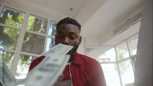 Surprised and cheerful young african man catching lots of money from ATM cash machine. Portrait of attractive afro-american guy making a withdrawal in a bank.