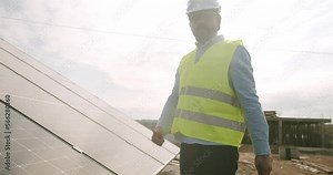 Connection and mounting of solar panels. Technician installing solar panels on metal stand. Technician working with electrical screwdriver installing solar panel to metal platform system.