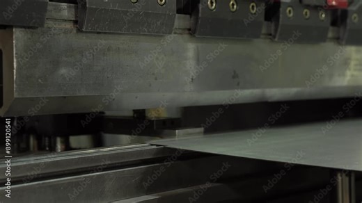 The employee hands are not bending the large parts of the metal on the bending machine, closeup. The CNC operator bending a metal product bends.