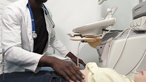 Doctor is making abdominal ultrasound for child girl using scanner, side view.