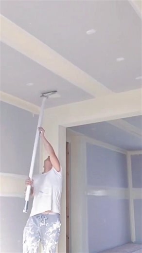 Worker Sanding Drywall Ceiling Smoothly with Long Pole Tool
