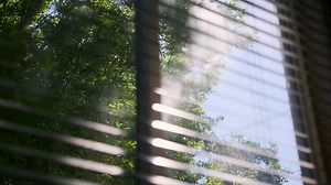 Close up view of Sun shining through window blinds close. Slow motion view footage