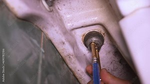 Connecting faucet to water supply using flexible braided hoses, plumber pulls hose into faucet . Connecting tap to water supply with braided hose. Connection to home water system.