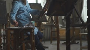 Loft-studio for the artist: a female artist paints a painting on canvas. A woman artist paints in seclusion in an atmospheric and light workshop. Artist's workshop with creative objects