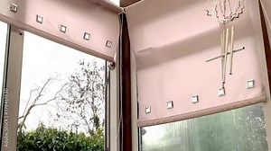 Strong wind through an open glass door to a room, blowing window blinds and hanging chimes.