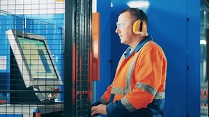 Computerized machine is getting operated by a factory worker