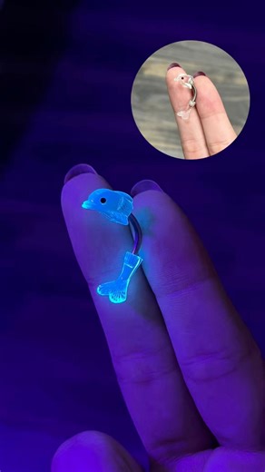 289K views · 2.7K reactions | Glow Belly Goals ✨ This dolphin belly ring glows under UV light — perfect for festivals, beach nights, or anywhere you wanna stand out. Fun, flirty, and ready to light up your look! #DolphinBellyRing #UVGlowJewelry #GlowUnderUV #PiercingVibes #FestivalPiercing #BellyRingGoals #CuteAndGlowing #BlacklightReady #BodyJewelryFun #SummerPiercingStyle | BodyJewelry.com | Facebook
