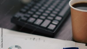 Business paperwork on office desk next to cup of coffee, extreme close up shot. Company documents containing charts and hot beverage on table in financial department workspace