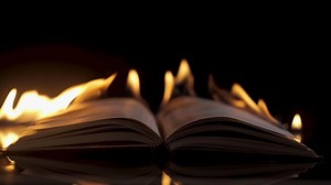 An open book is on fire. Big bright flame, burning paper on old publication. Bonfire conflagration in the dark. Book Burning - Censorship Concept