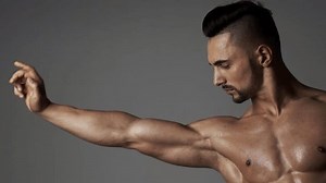 Muscular sexy man man flexing biceps. Male athlete, sportsman flexing bicep, looking at muscle biceps. Male Muscular biceps arm. Hand, man arm biceps Close-up. Strong, sexy and topless male model.