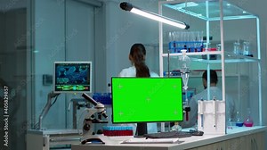 Team of scientists working in background of modern laboratory using computer with green screen, mockup display, chroma key monitor, analysing experiment evolution, high tech development lab.