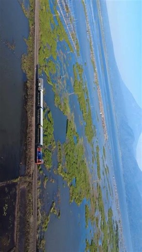a train around a lake that looks blue #drone #travel #nature
