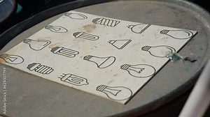 Old burnt out fluorescent lamps for recycling next to the lightbulb icon set on the paper on a metal barrel. Waste disposal, separate garbage collection and care for the environment