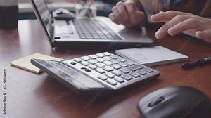Men's hands count on a calculator and enter data into a laptop. Close-up of an old calculator next to a laptop and Notepad. The accountant guy keeps a count