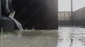 Heavy rain falling on concrete with water pouring out of down spout