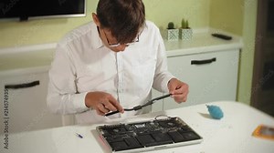 A man is repairing a laptop. The concept of computer repair. Close up of man repair laptop motherboard with a screwdriver. Maintenance of the hardware of the motherboard. Disc holder, computer repair