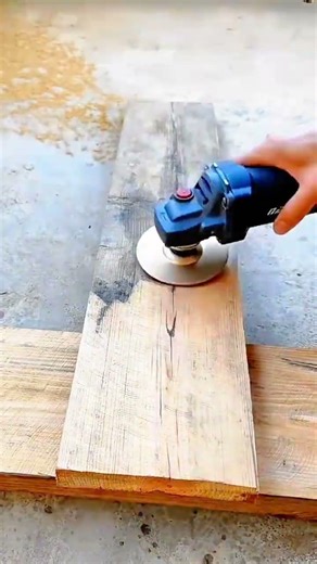 sanding the wood beam surface using a handheld angle grinder with a metal carving disc attachment