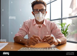 Man in a mask talking on a video call Stock Photo - Alamy