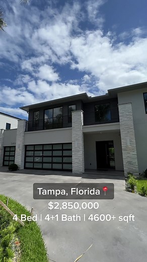 This modern home in the Palma Ceia area of South Tampa is a perfect blend of luxury, style, and functionality. The circular concrete driveway welcomes you with a well-manicured landscape of mature royal palm trees and spa stones. The house boasts an elegant mix of white natural stacked stone and bronzed aluminum accents, creating a contrast of colors and textures that impresses at first glance. Upon entering, the 8-foot modern front door immediately draws attention. The foyer has an entire wall