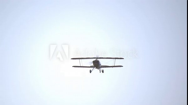 Front Low Angle View of a Flying Biplane with Spinning Propeller SLOMO