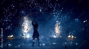 Fantastic fire show performed by the female artist. Woman moves the stage props that produce sparks of firework.