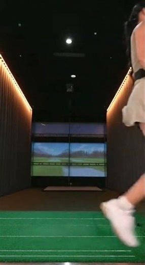 Stylish woman perfecting her golf swing at indoor facility