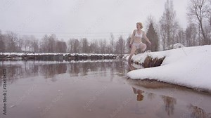An experienced ice bathing woman in her 40s enters a cold lake