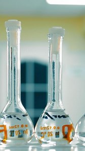 Volumetric Flasks in Science Lab. Row of volumetric flasks with clear liquid in a scientific laboratory.