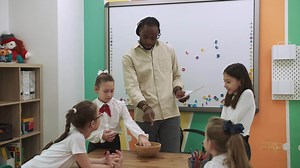 An African American teacher teaches a group of children English by playing with them.School for Children, Teaching Adolescents, Gain Knowledge, Learn the Language.