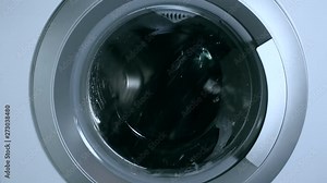 Washing things in the washing machine. The rotation of the drum of the washing machine close-up.