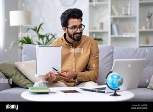 Young male teacher teaching remotely from home, hispanic using laptop for video call and communication and teaching students remotely, explaining new school material smiling Stock Photo - Alamy