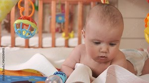 Little boy crawls on a multi-colored rug designed for the development of a child.The concept of active healthy young children. 4K UHD still video camera, 2x slow motion.