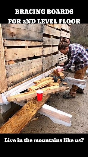 Pallet House Build: adding Bracing Boards to the joists of the floor. We are using our diy joist hangers to frame in and install laminated pallet beams for the second level of our Pallet house. #offgridliving #palletwood #floorjoists #joisthangers#diyhome #palletproject #shtf #tinyhousebuild #mountainliving #howtobuild We are building a house out of pallets on our off grid mountain! We are not doing this because it's trendy or cool. We are doing this because it is necessary! Follow to see how ma