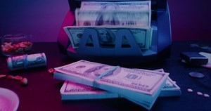 A stack of money sitting on a table next to a cash register