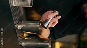 vertical video Professional barman using beaker pours alcoholic drink into shaker with one hand and holds bottle in other
