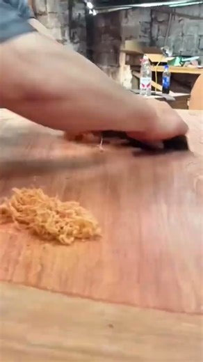 A man is scraping wood surface using sharp tool