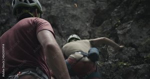 Climber with helmet protect partner who start rock climb ascend belay rope for safety outdoors lifestyle sport in nature over shoulder