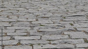 Camera moving forward over cobblestone pavement with grass