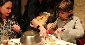 Mom and child eating fondue for supper, Candid authentic scene of family eating traditional swiss cuisine, fondue2