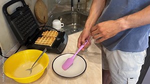 Home cook making delicious waffles in kitchen with waffle maker. Step by step process from pouring batter to plating warm waffles