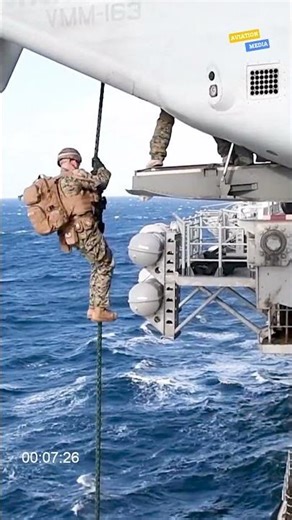 Marines descending using a fast rope from an aircraft into the hangar of the USS Boxer (LHD 4)